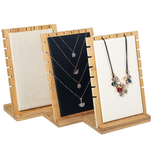 Three wooden jewelry display stands with necklaces on a white background