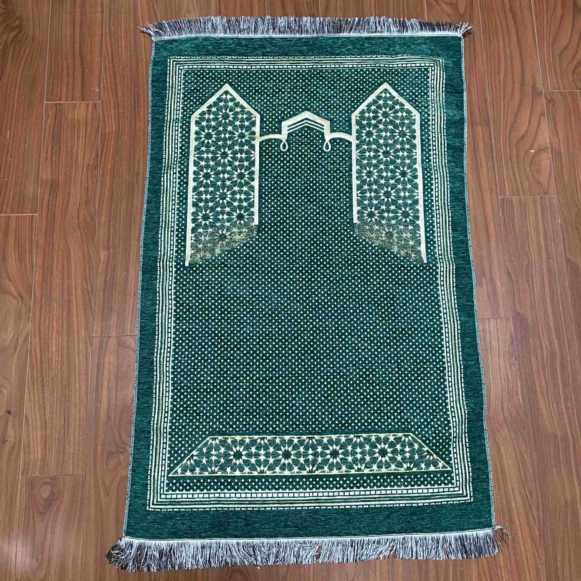Green prayer mat with white patterns on a wooden floor