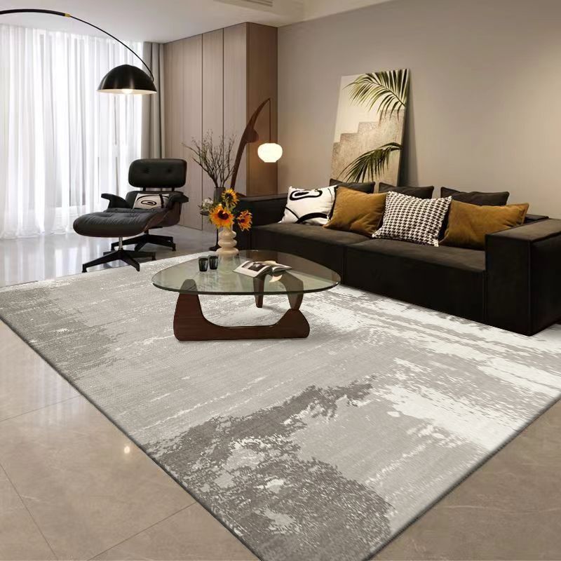 Modern living room with a gray rug, black sofa, and decorative elements.