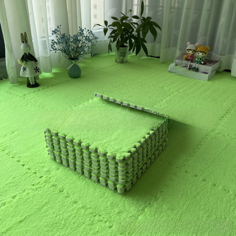 Green interlocking foam mats on a floor with decorative items in the background.