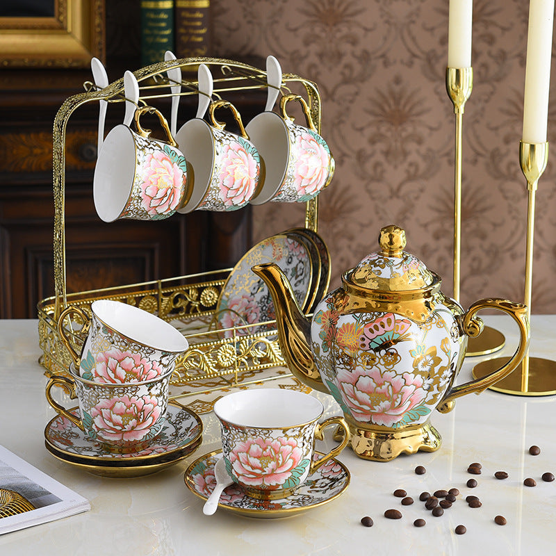 Decorative tea set with floral patterns on a table with coffee beans.