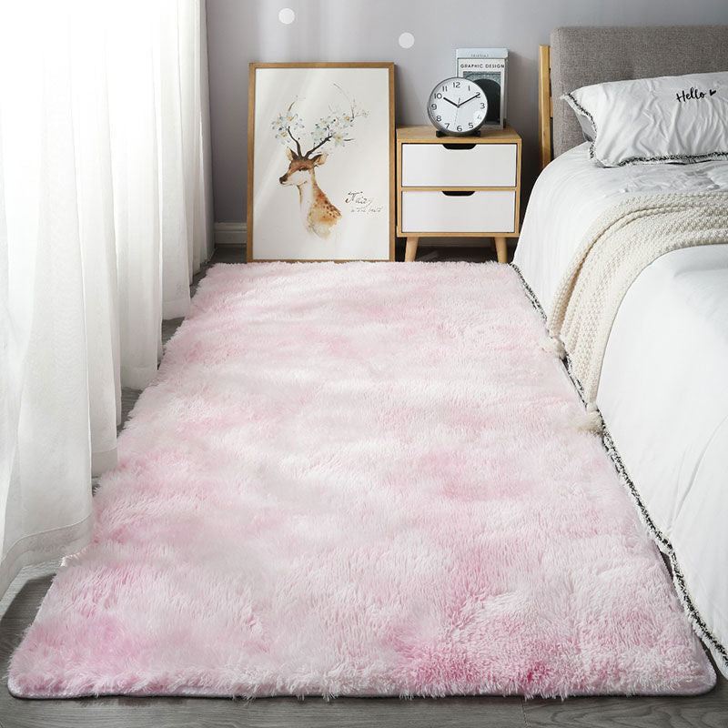 Pink rug in a bedroom setting with a bed, nightstand, and wall art.