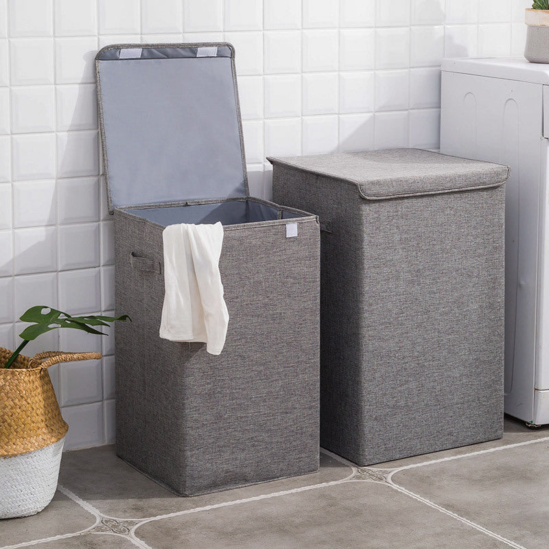 Two gray laundry baskets with lids in a tiled room.
